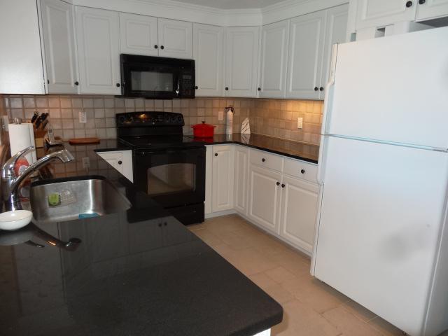 258 Huckins Neck Road Centerville, MA 02601 - Photo 13 of 30 a kitchen with granite countertop white cabinets and stainless steel appliances