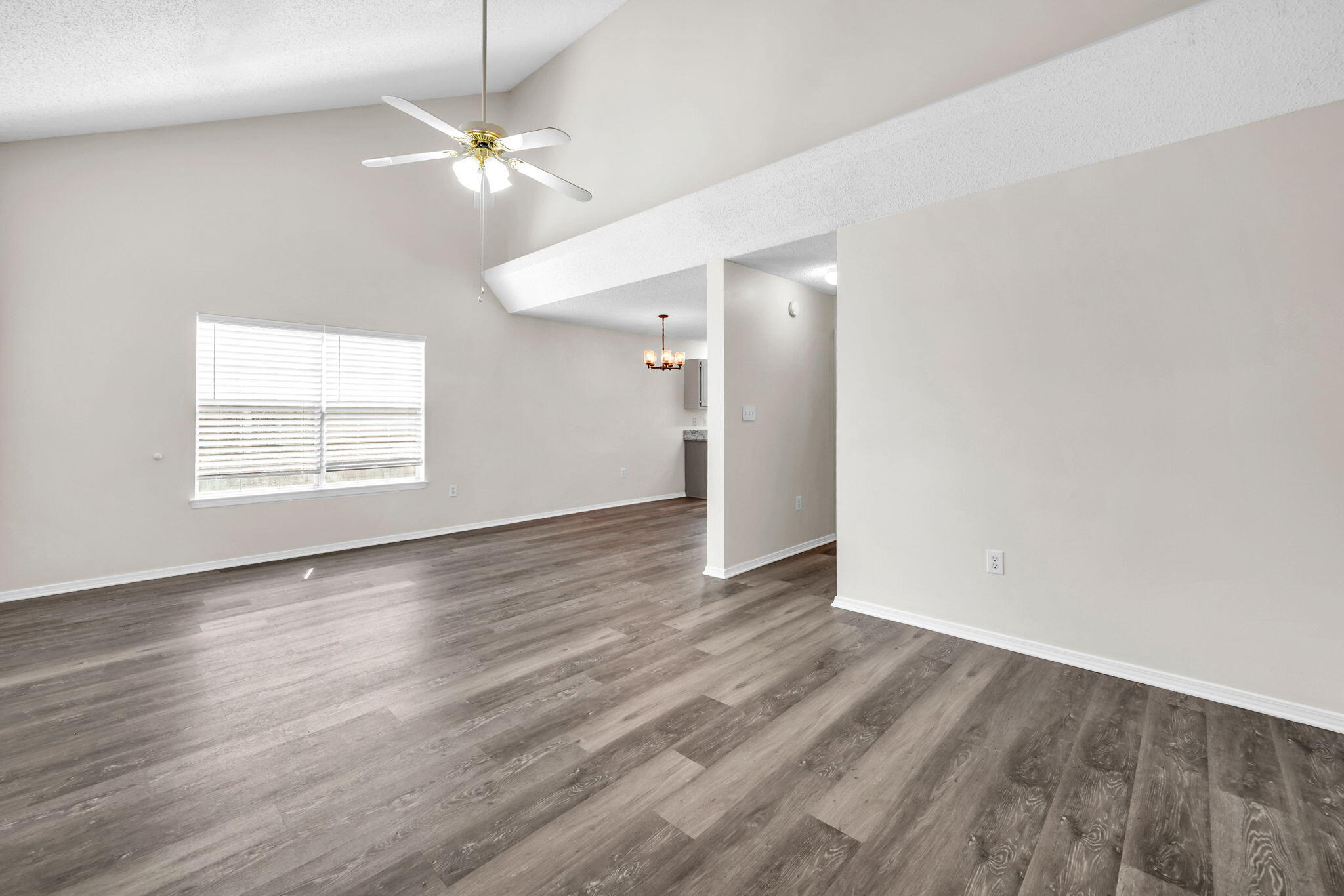 1036 Blue Ridge Drive Fort Walton Beach, FL 32547 - Photo 11 of 31 an empty room with wooden floor chandelier fan and windows