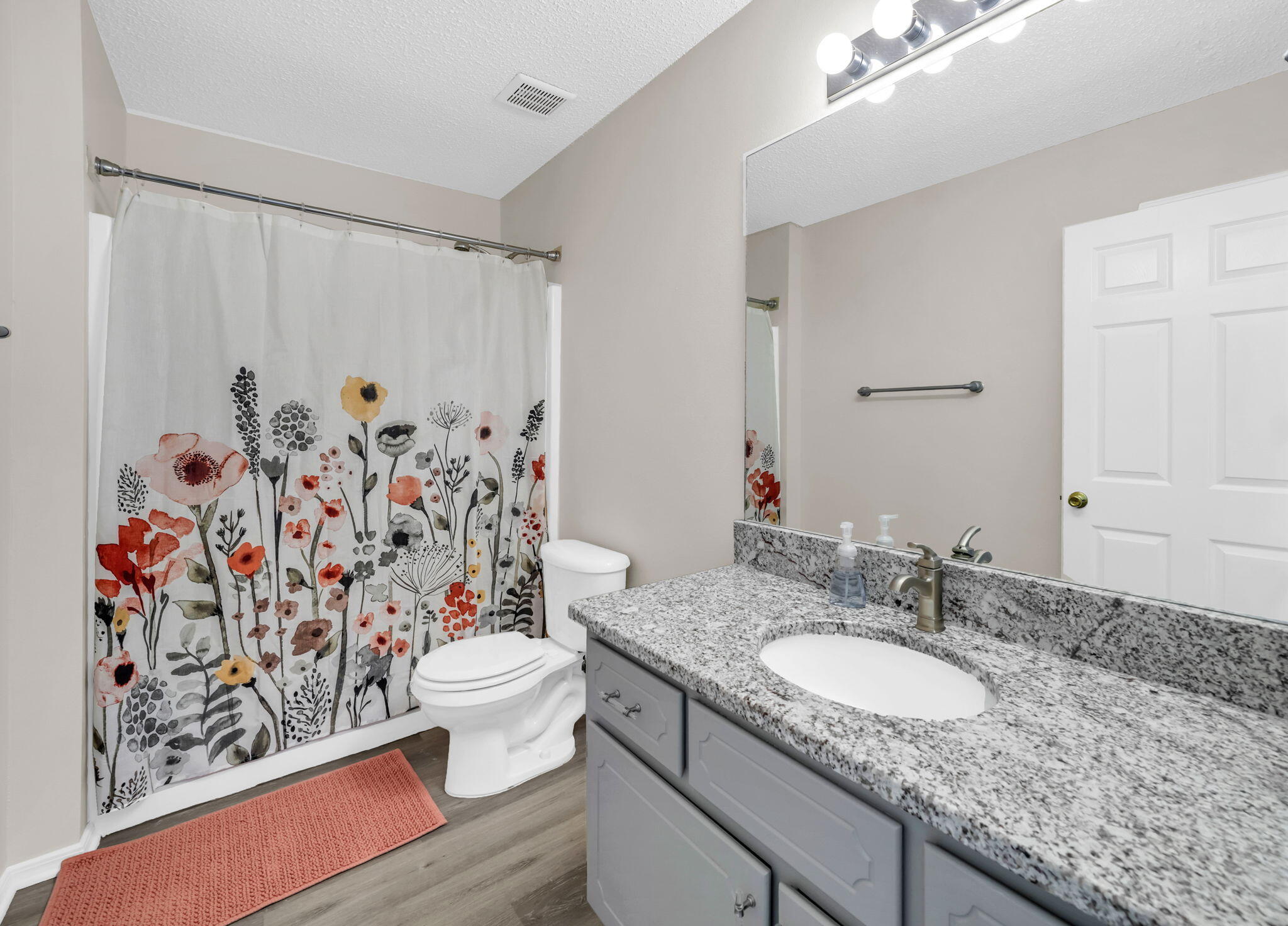 1036 Blue Ridge Drive Fort Walton Beach, FL 32547 - Photo 18 of 31 a bathroom with a granite countertop sink a toilet and a shower curtain