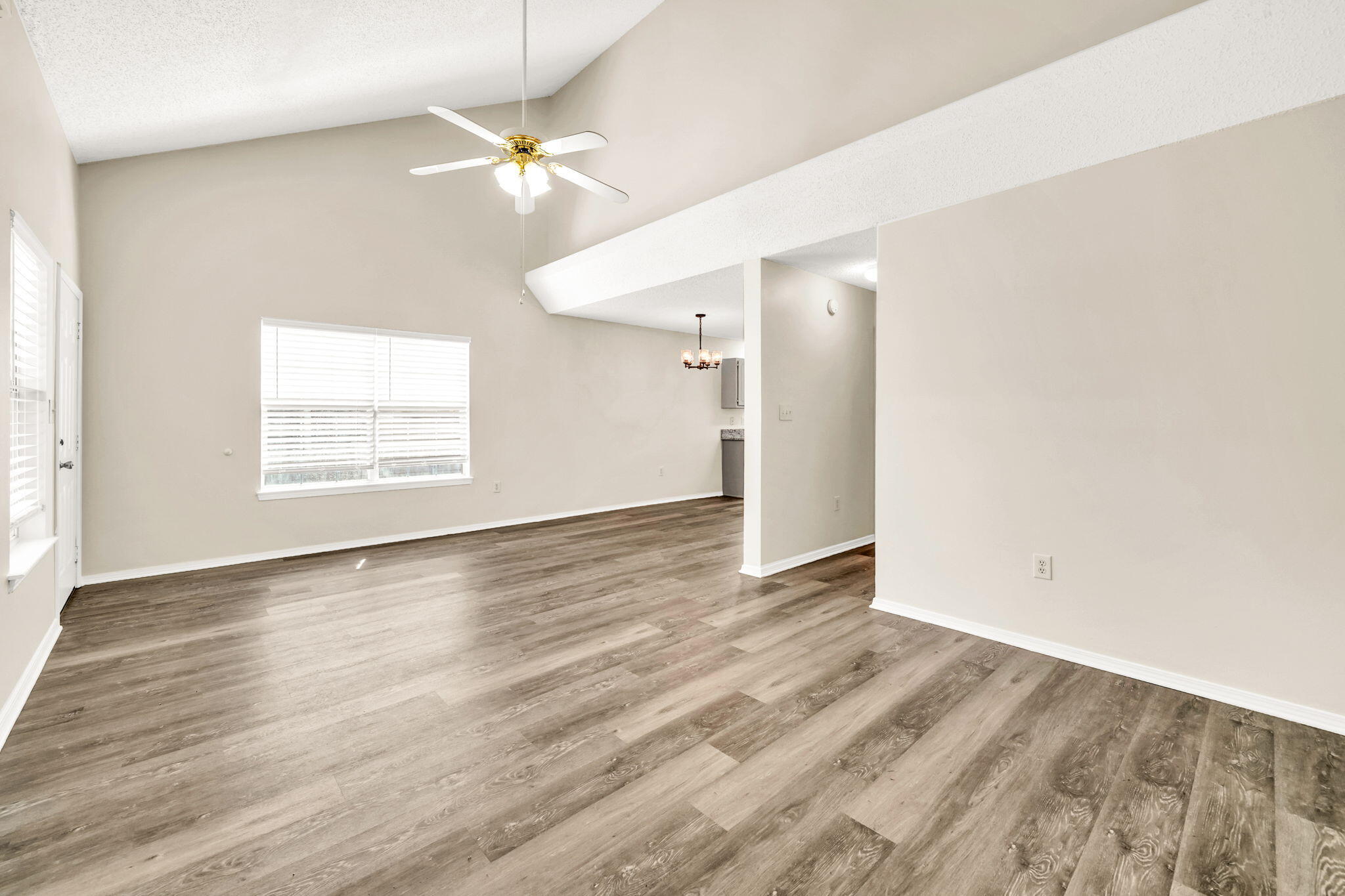 1036 Blue Ridge Drive Fort Walton Beach, FL 32547 - Photo 22 of 31 an empty room with wooden floor chandelier fan and windows