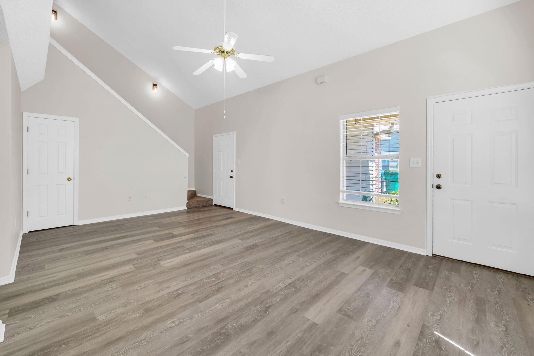 1036 Blue Ridge Drive Fort Walton Beach, FL 32547 - Photo 6 of 31 an empty room with wooden floor chandelier fan and windows