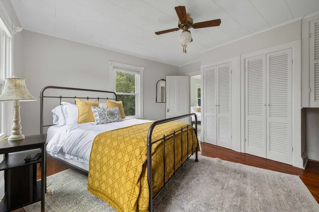 a bedroom with a bed a table and windows