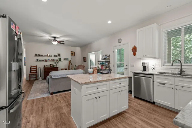 a kitchen with a sink dishwasher a stove and white cabinets with wooden floor