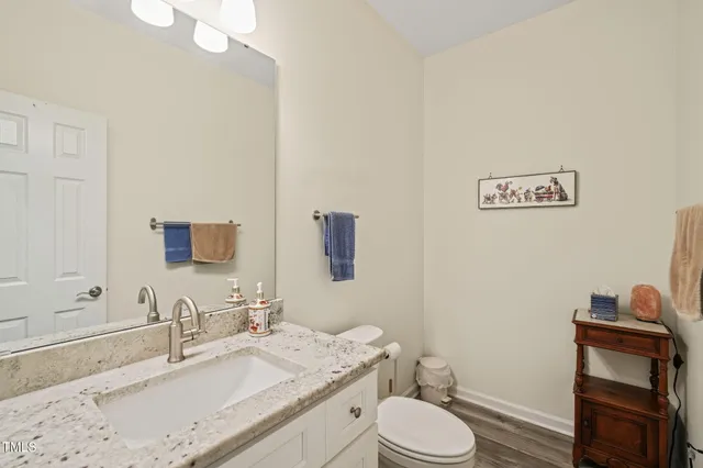 a bathroom with a granite countertop sink mirror vanity and toilet