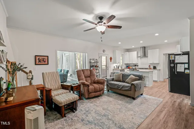 a living room with furniture kitchen view and a chandelier