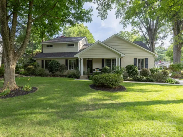 a view of a house with a yard potted plants and large tree