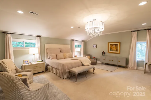 a spacious bedroom with a bed a chandelier and a window