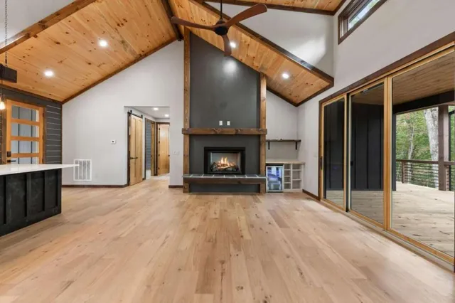 a view of an empty room with wooden floor fireplace and a window