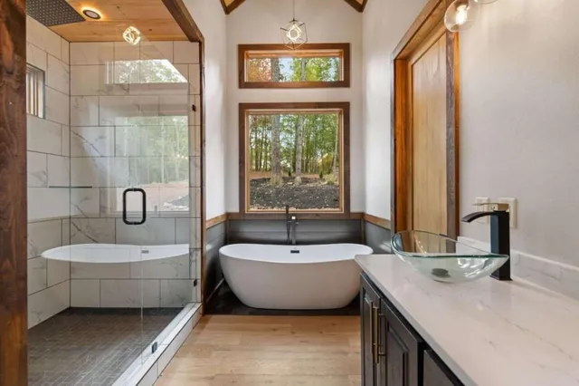 a bathroom with a double vanity sink bathtub and next to a window