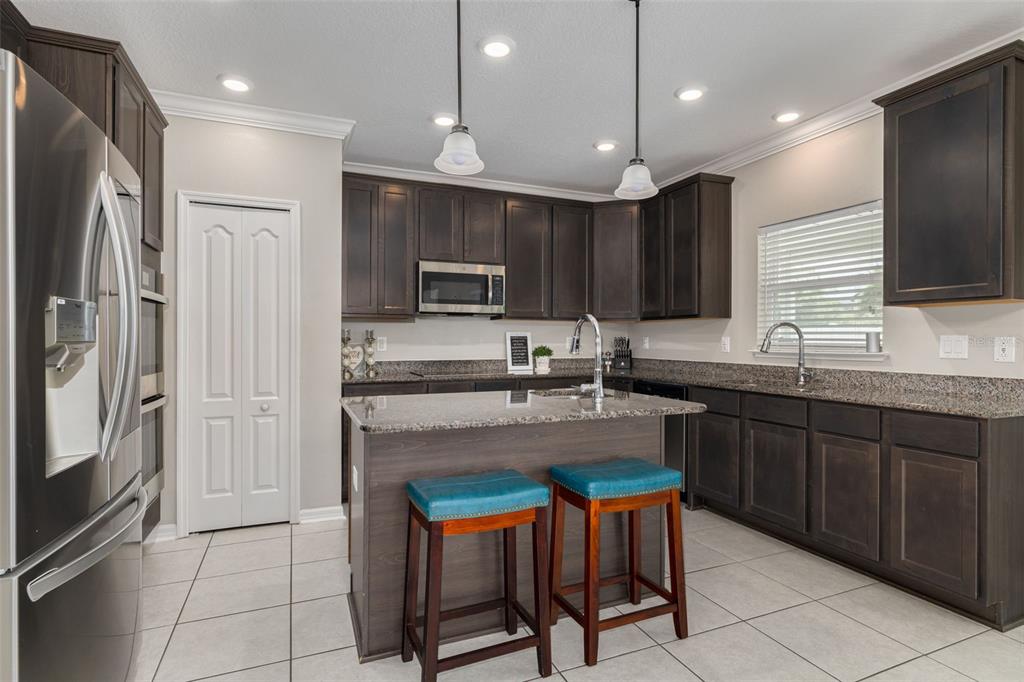 7242 Landmark Drive Spring Hill, FL 34606 - Photo 12 of 45 a kitchen with kitchen island granite countertop wooden cabinets and refrigerator