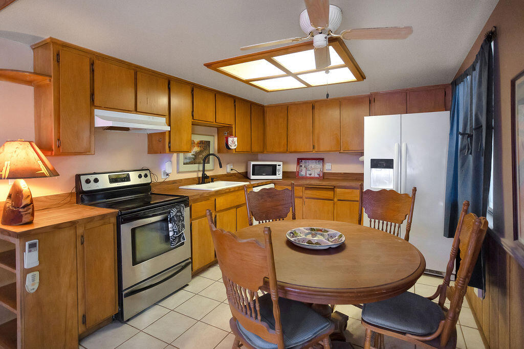 5134 Malin Way Yucca Valley, CA 92284 - Photo 11 of 27 a kitchen with stainless steel appliances a table chairs and a refrigerator