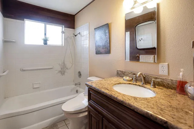 a bathroom with a granite countertop toilet a sink and a bathtub