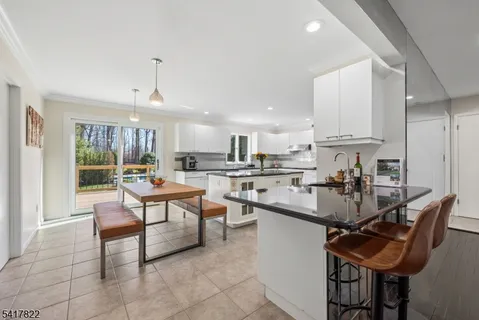 a kitchen with stainless steel appliances kitchen island granite countertop a sink a stove a dining table and chairs