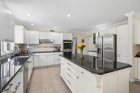 a kitchen with stainless steel appliances granite countertop a sink refrigerator and cabinets