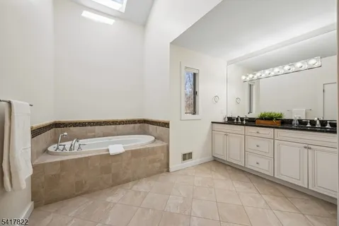 a spacious bathroom with a tub sink and mirror