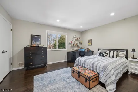 a spacious bedroom with a bed and wooden floor