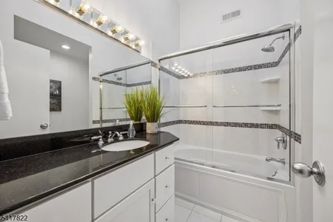 a bathroom with a granite countertop sink a shower and a mirror