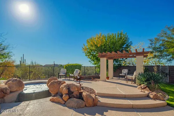 a view of a patio with couches and table and chairs under an umbrella with large trees