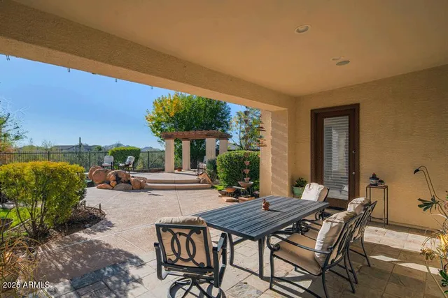 a view of a patio with a table and chairs under an umbrella next to a yard