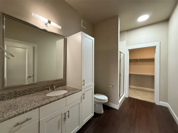 a bathroom with a granite countertop sink toilet and large mirror