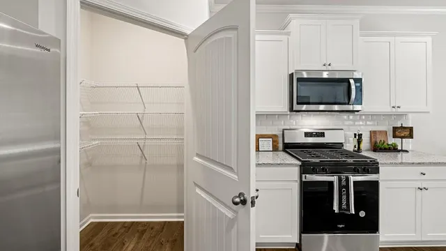a living room with stainless steel appliances furniture and a kitchen view