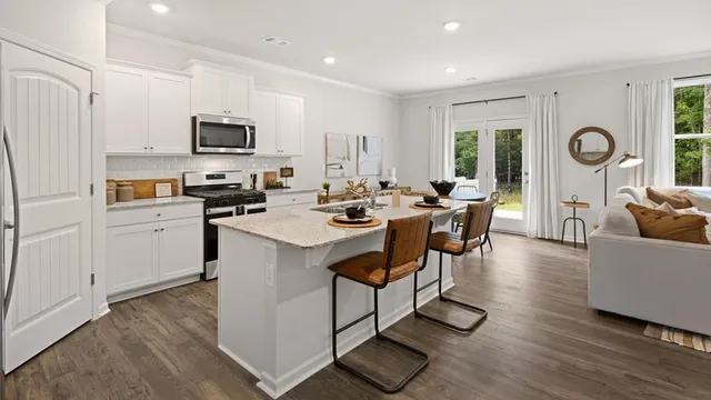 a kitchen with stainless steel appliances a stove top oven a refrigerator a sink and a dining table with wooden floor