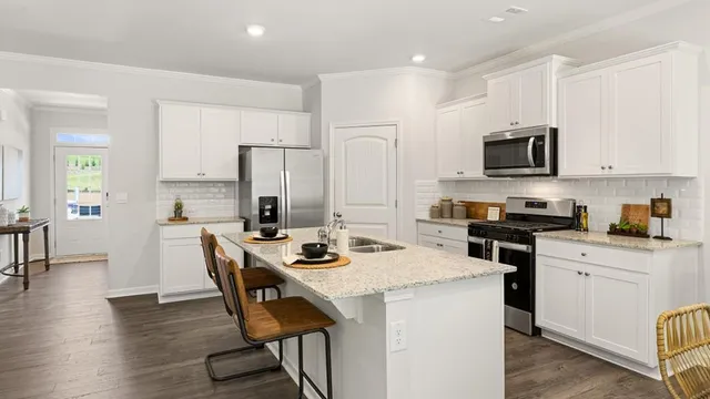 a kitchen with stainless steel appliances granite countertop a stove top oven a sink dishwasher a dining table and chairs with wooden floor