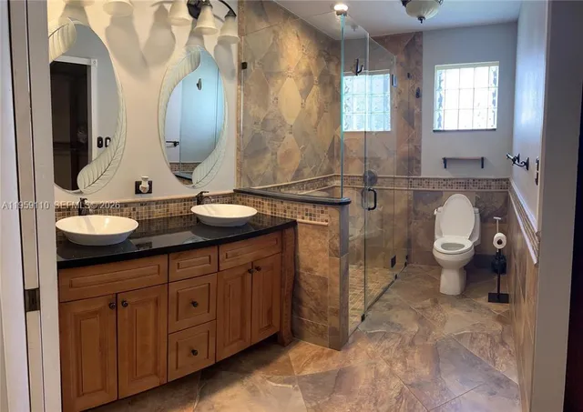 a bathroom with a granite countertop toilet sink and mirror