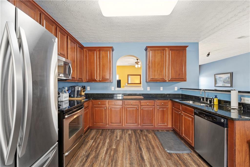 2708 Oakmont Way Monroe, GA 30656 - Photo 8 of 40 a kitchen with stainless steel appliances granite countertop refrigerator a sink dishwasher a stove top oven a refrigerator with wooden cabinets and floor