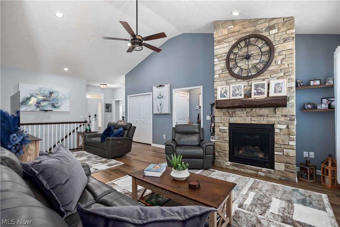 109 West Spring Drive Elyria, OH 44035 - Photo 15 of 46 Living area featuring a floor-to-ceiling stone fireplace with a wood mantel, vaulted ceiling with a ceiling fan, recessed lighting, and wood-finish flooring