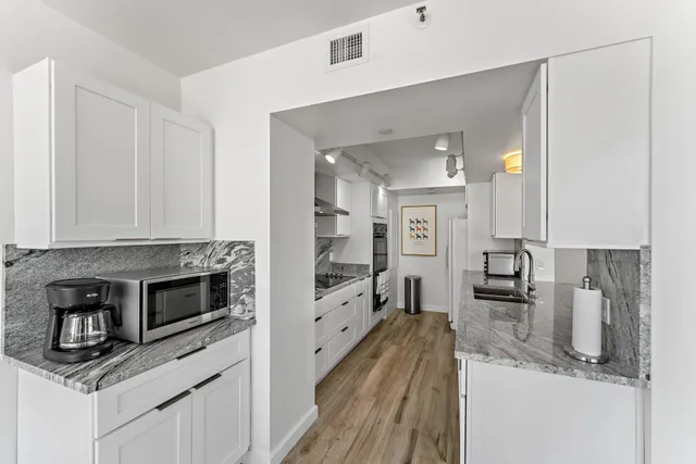 a large kitchen with stainless steel appliances granite countertop a lot of counter space and wooden floor