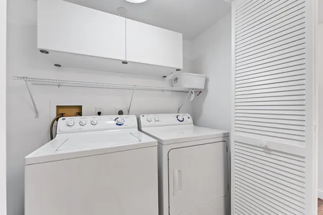 a living room with couches chandelier and a dining table with wooden floor