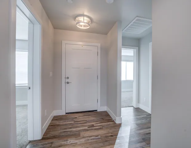 a view of a hallway with wooden floor and a window