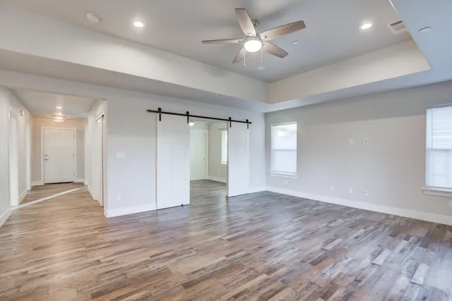 a view of an empty room with a window and wooden floor