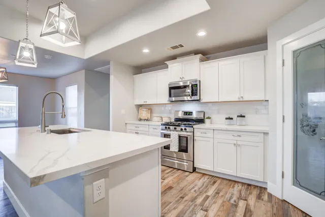 a kitchen with stainless steel appliances kitchen island a sink a stove a microwave and cabinets