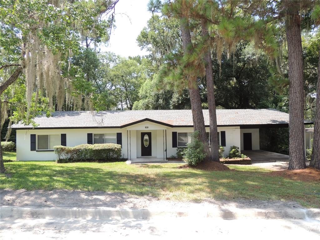 112 Northwest 29th Street Gainesville, FL 32607 - Photo 1 of 1 a view of a white house with a swimming pool and a lawn chairs under a large tree