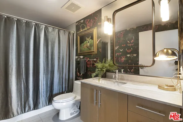a bathroom with a granite countertop sink toilet and mirror