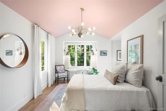 a spacious bedroom with a bed a mirror and a window