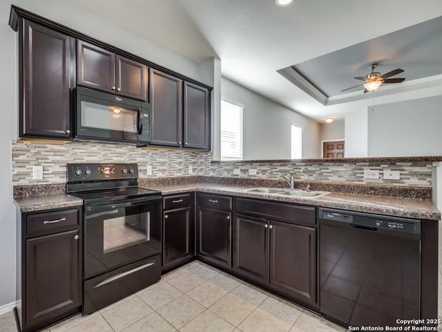 a kitchen with granite countertop stainless steel appliances a sink stove and cabinets