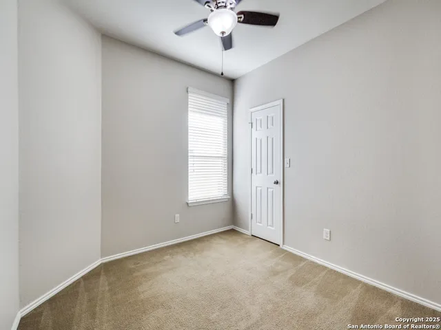 an empty room with windows and ceiling fan
