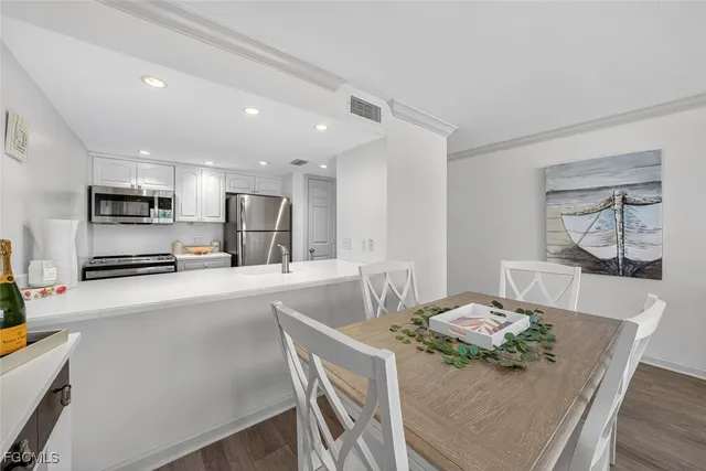 a kitchen with stainless steel appliances kitchen island granite countertop a sink a stove a dining table and chairs