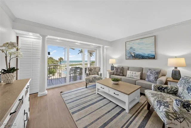 a living room with furniture large windows and wooden floor