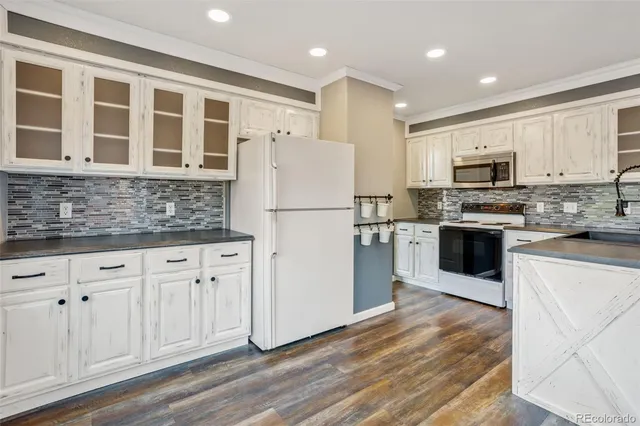 a kitchen with granite countertop a refrigerator oven a sink and cabinets