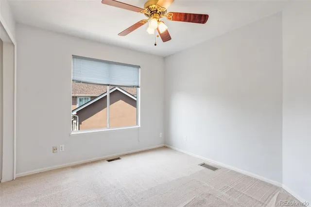 an empty room with chandelier fan and windows