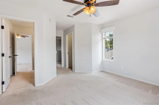 a view of an empty room and window with a fan