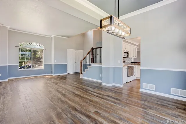a view of a room with wooden floor staircase and a kitchen