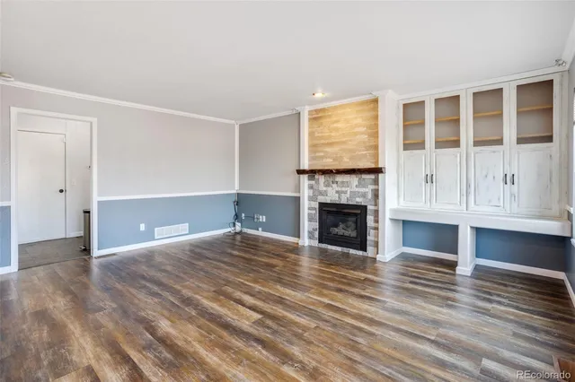 a view of an empty room with wooden floor fireplace and a window