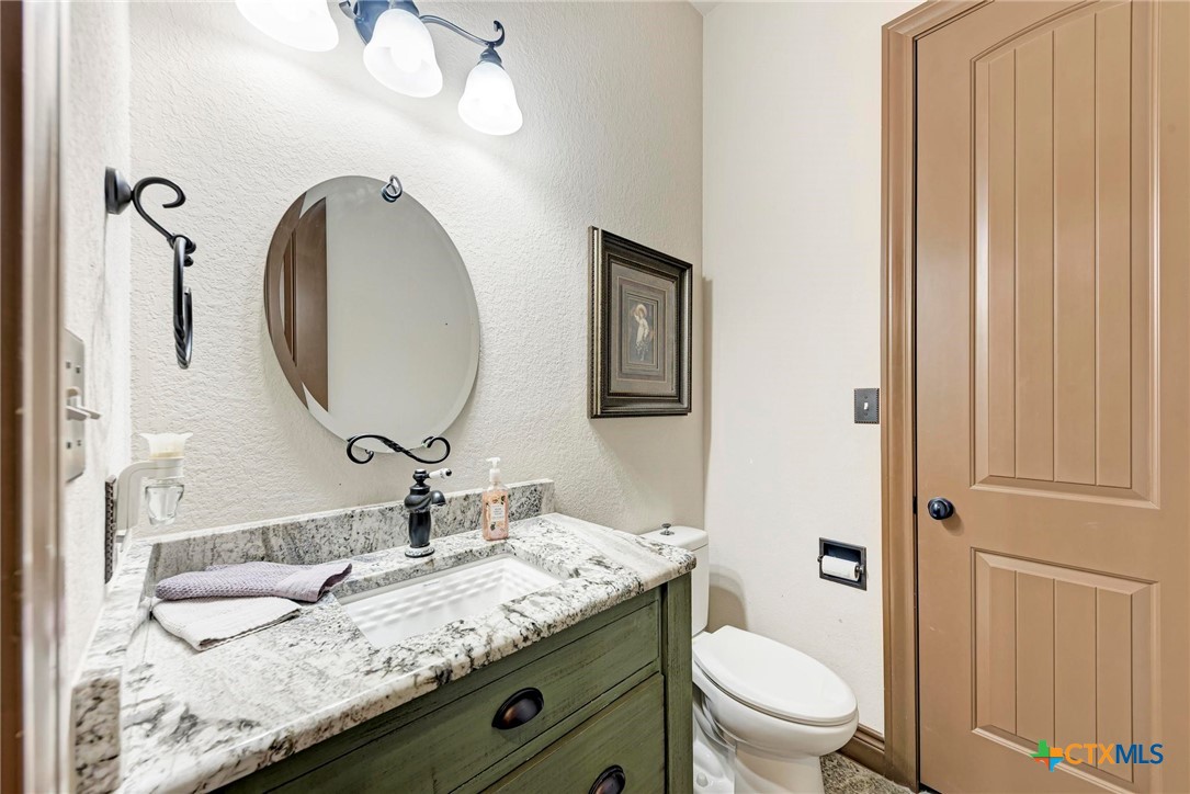 1325 County Road 106 Lampasas, TX 76550 - Photo 25 of 48 a bathroom with a granite countertop toilet a sink and a mirror