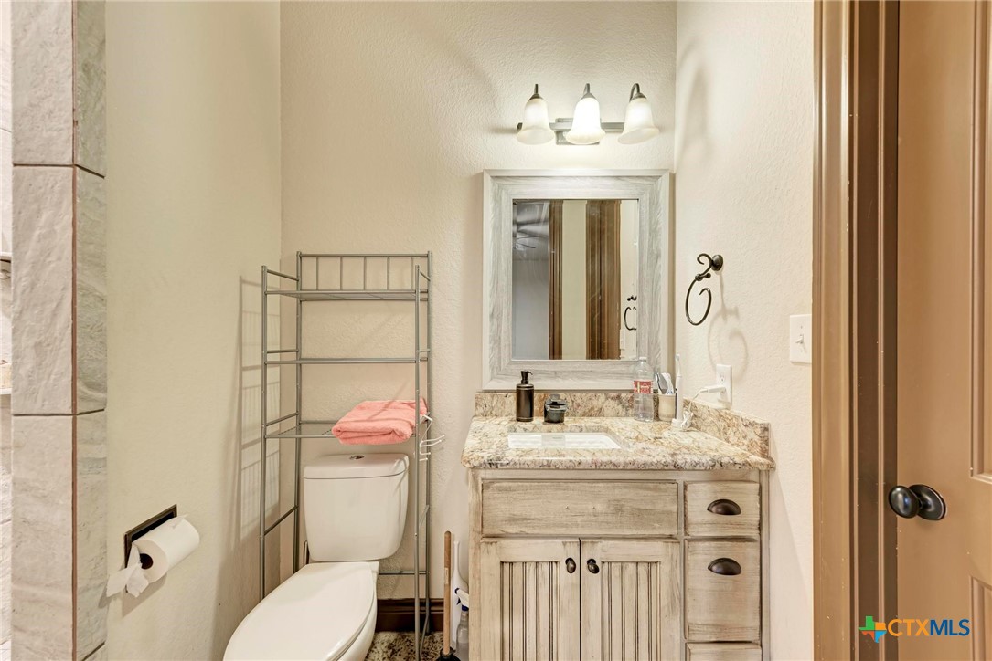 1325 County Road 106 Lampasas, TX 76550 - Photo 33 of 48 a bathroom with a granite countertop sink a toilet and shower