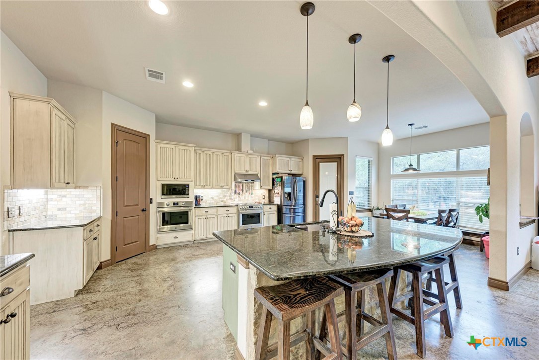 1325 County Road 106 Lampasas, TX 76550 - Photo 4 of 48 a kitchen with stainless steel appliances granite countertop a stove top oven a sink dishwasher and white cabinets with wooden floor